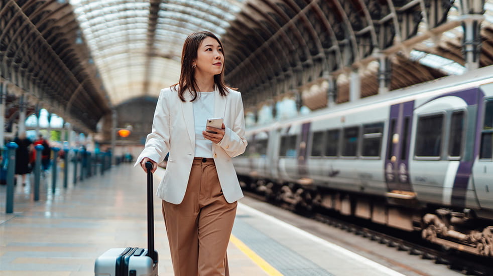 Young business woman with luggage walking on the platform at train station